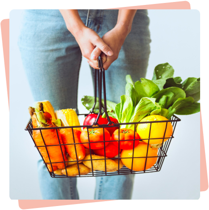 Une personne tenant un panier de courses rempli de fruits et légumes sains